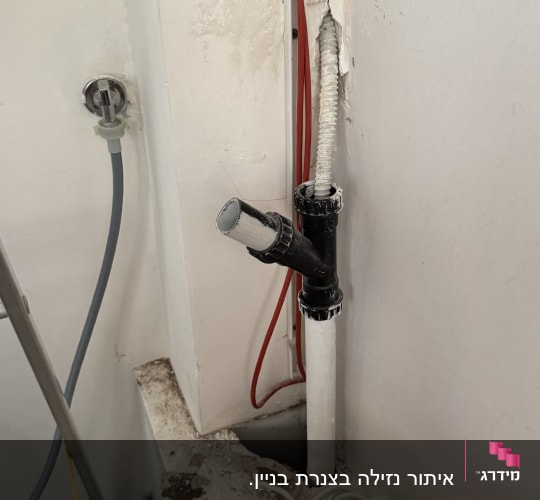 צינור פלסטיק לבן עם חיבורים שחורים בקיר